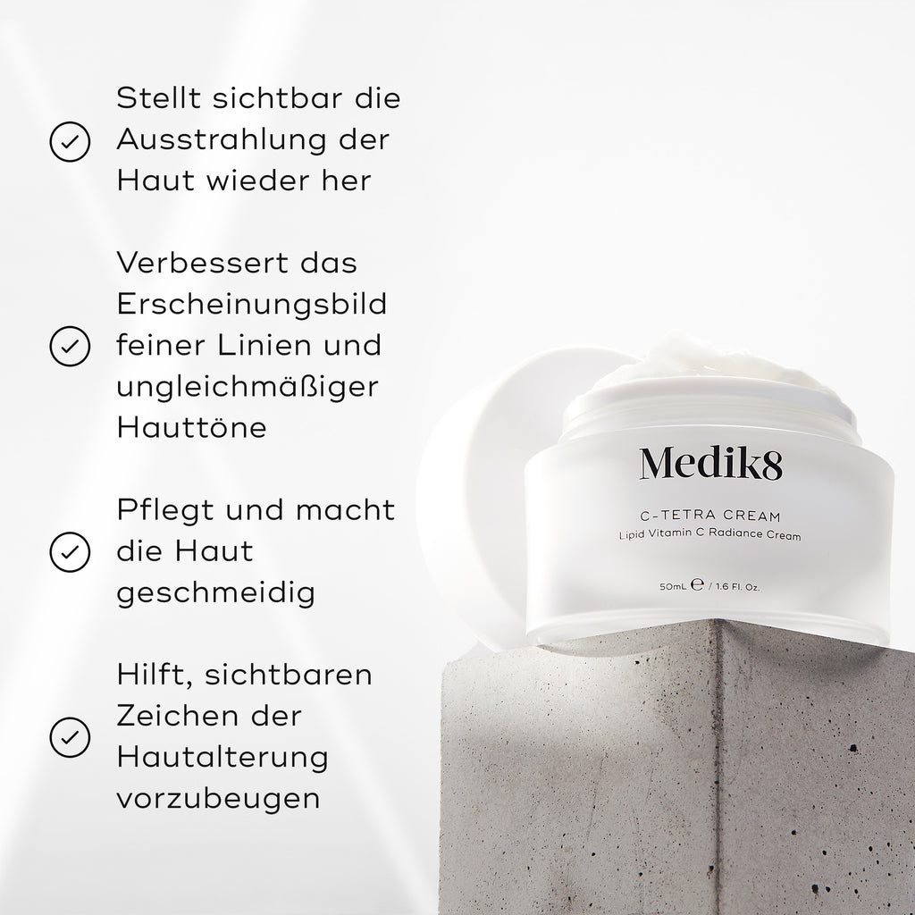 Medik8 C-Tetra Cream-Glas auf einem grauen Steinblock vor weißem Hintergrund mit sanften Lichtstrahlen dargestellt. Das Bild zeigt vier Häkchen-Behauptungen: Sichtbare Wiederherstellung der Hautstrahlung, Verbessert das Erscheinungsbild von feinen Linien & ungleichmäßigem Hautton, Pflegt & macht die Haut weich, Hilft, sichtbare Zeichen der Hautalterung zu verhindern