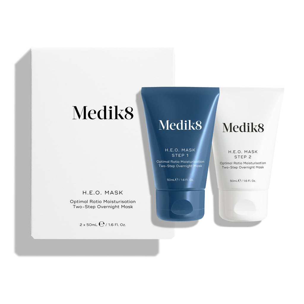 Ein weißer Produktkarton für die H.E.O.-Maske steht neben zwei Schläuchen der Maske.