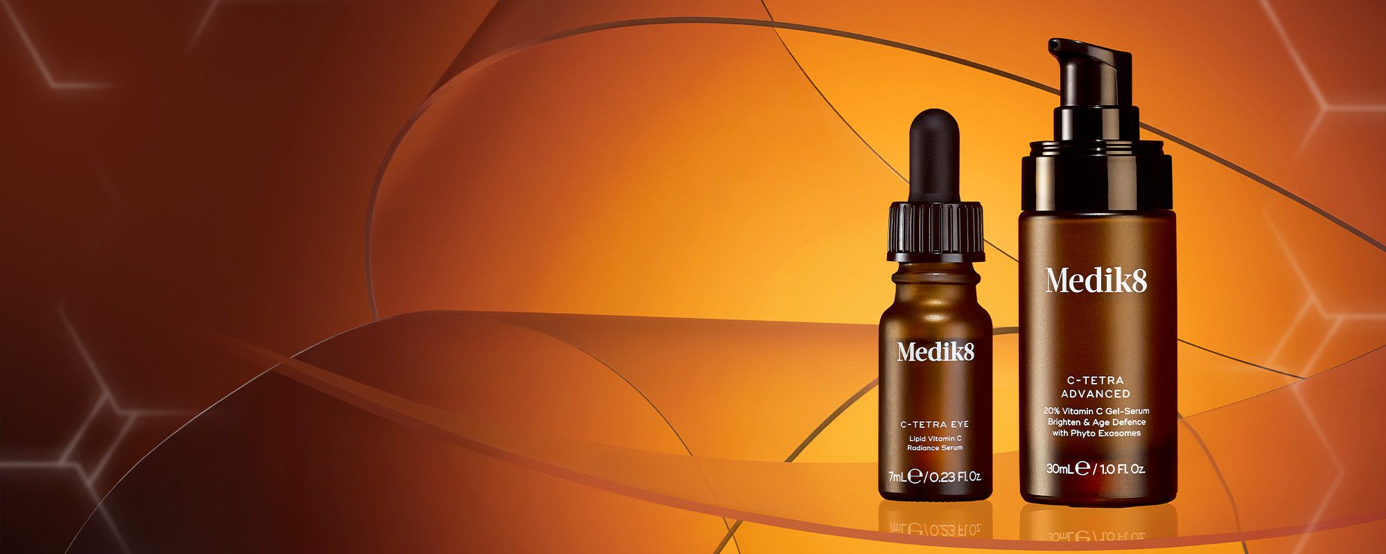 Medik8 C-Tetra Produktduo auf einem warmen, orangefarbenen Hintergrund mit abstrakten molekularen Strukturen. Zu sehen sind das C-Tetra Eye Serum (7ml) mit Pipette und das C-Tetra Advanced Serum (30ml) mit Pumpspender. Die Flaschen stehen auf einer spiegelnden Glasoberfläche.