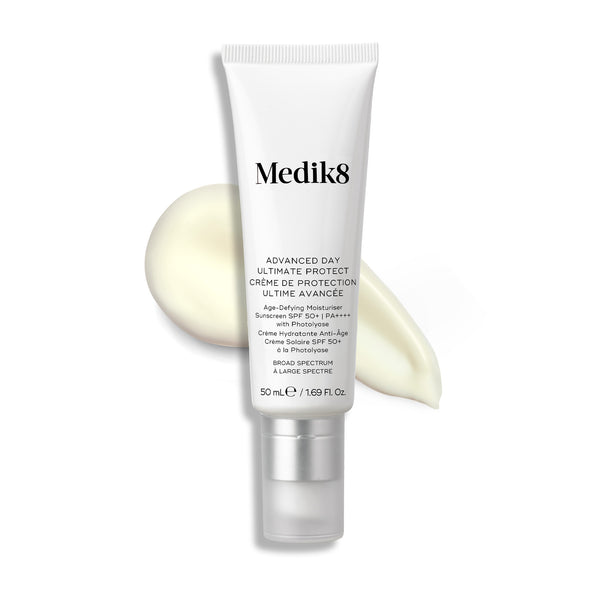 Eine weiße Tube Advanced Day Ultimate Protect steht aufrecht, daneben ein Auftrag heller Creme.
